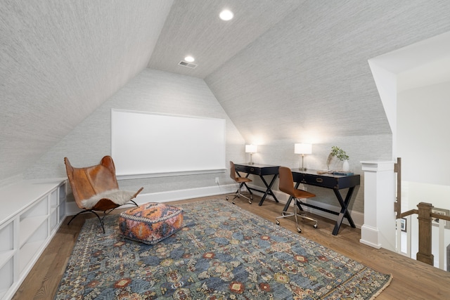 living area with lofted ceiling, hardwood / wood-style floors, and a textured ceiling