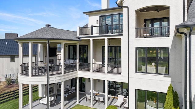 rear view of house with ceiling fan, a patio, and a balcony