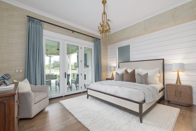 bedroom featuring french doors, hardwood / wood-style floors, a chandelier, access to outside, and ornamental molding