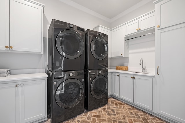 laundry room featuring ornamental molding, stacked washer and clothes dryer, cabinets, and sink