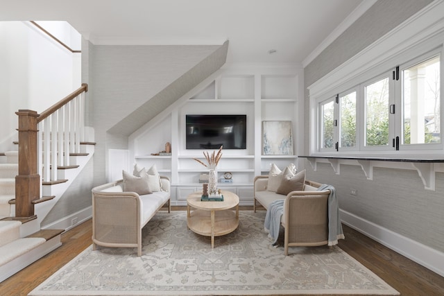 sitting room with built in shelves, ornamental molding, and hardwood / wood-style flooring