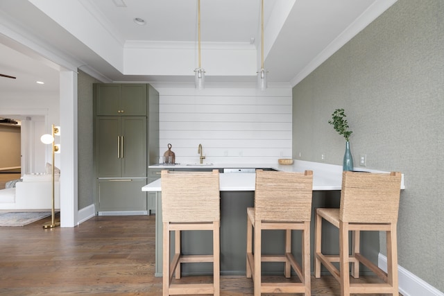 kitchen featuring green cabinets, crown molding, kitchen peninsula, dark wood-type flooring, and a kitchen breakfast bar