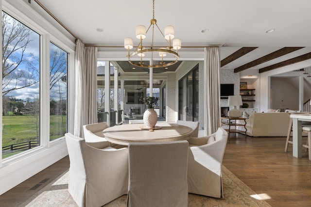 dining space with a healthy amount of sunlight, hardwood / wood-style floors, and a notable chandelier