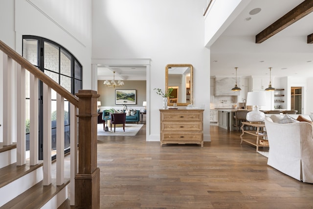 foyer with dark wood-type flooring, a high ceiling, an inviting chandelier, and beamed ceiling