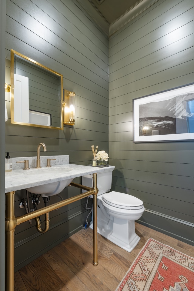 bathroom with toilet, hardwood / wood-style flooring, and wooden walls