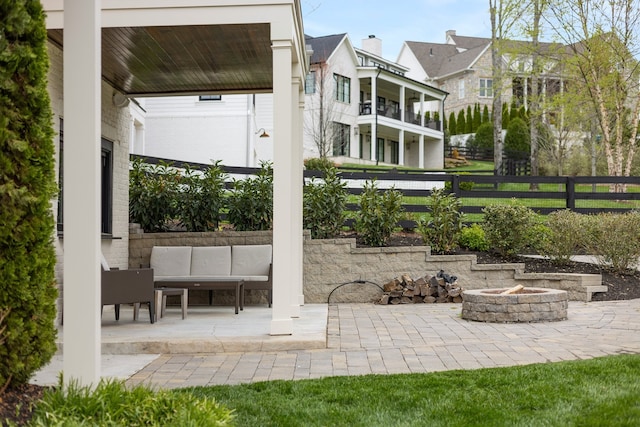 view of patio featuring a balcony and an outdoor living space with a fire pit