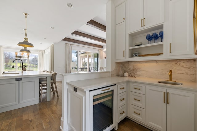 kitchen featuring beverage cooler, plenty of natural light, beam ceiling, and sink