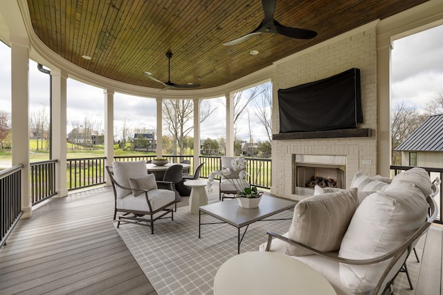 sunroom / solarium featuring an outdoor brick fireplace, a healthy amount of sunlight, ceiling fan, and wooden ceiling