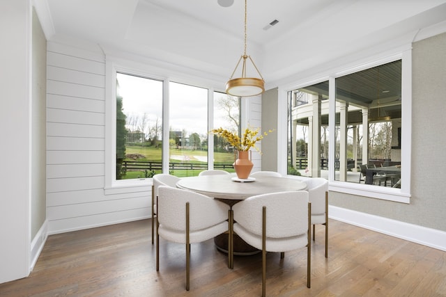 dining space featuring a healthy amount of sunlight, wood walls, and dark hardwood / wood-style floors