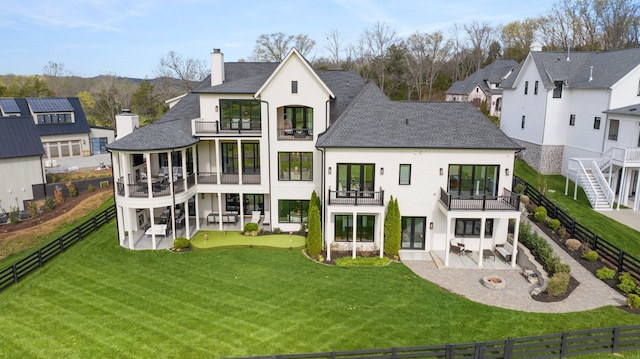 rear view of property featuring a balcony, a yard, and a patio