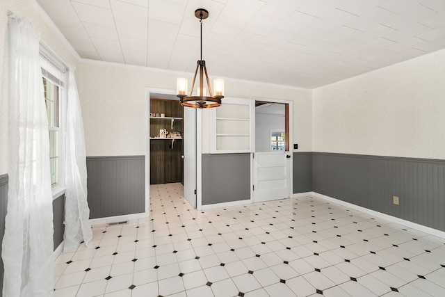 dining room featuring wooden walls, a chandelier, crown molding, and a healthy amount of sunlight