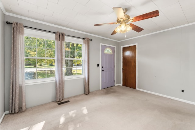 carpeted foyer featuring ceiling fan and crown molding