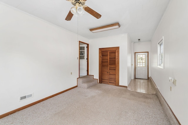 unfurnished bedroom featuring a closet, light colored carpet, and ceiling fan