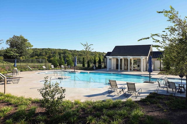 pool featuring a patio area, fence, and an outbuilding