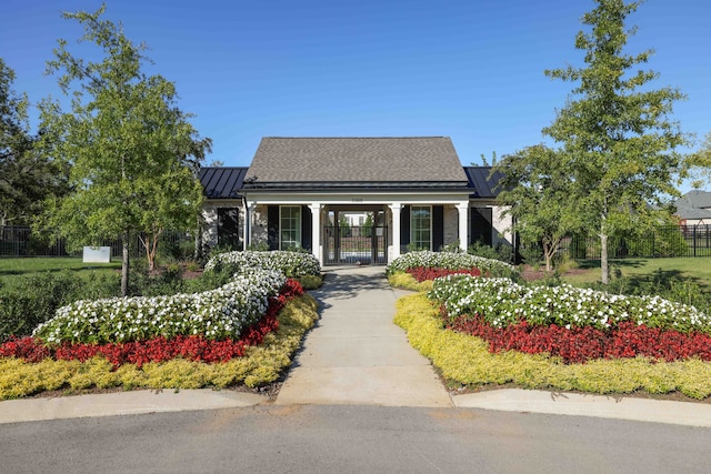 view of front facade featuring a standing seam roof, a gate, fence, and metal roof