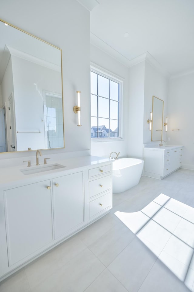 bathroom with a soaking tub, two vanities, a sink, crown molding, and tile patterned floors