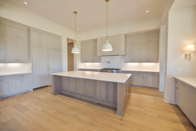 kitchen featuring light wood-style flooring, a center island, crown molding, decorative backsplash, and range