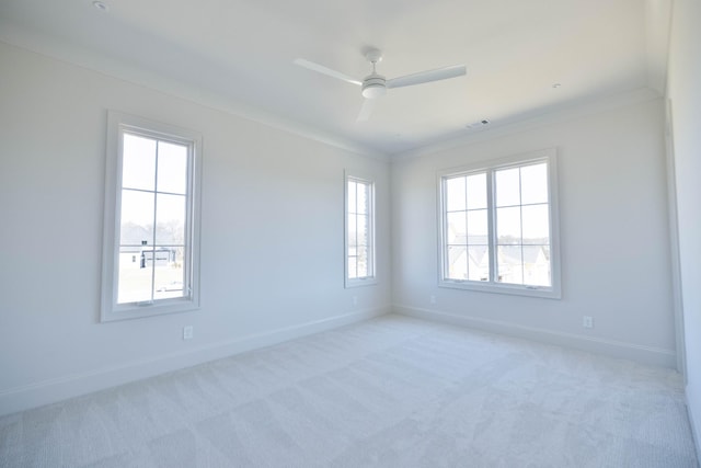 empty room with baseboards, light colored carpet, ornamental molding, and a ceiling fan