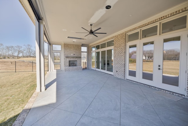 view of patio with a ceiling fan, fence, and an outdoor brick fireplace