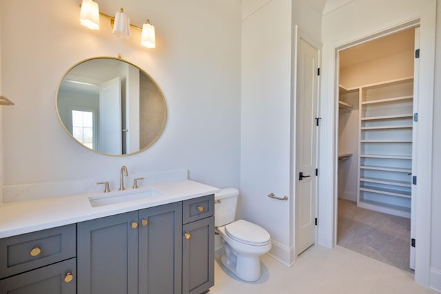 bathroom with vanity, a walk in closet, and toilet