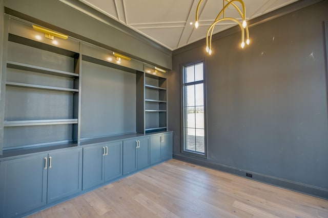 unfurnished room featuring built in shelves, baseboards, and light wood-type flooring