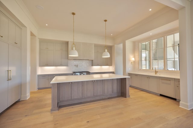 kitchen with a spacious island, light wood-style flooring, light countertops, crown molding, and tasteful backsplash