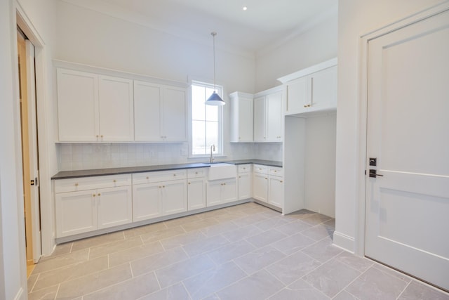 kitchen featuring dark countertops, white cabinetry, and a sink