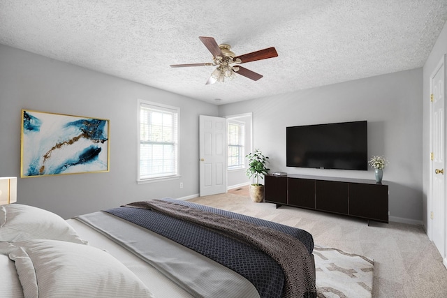 carpeted bedroom with a textured ceiling, baseboards, and ceiling fan