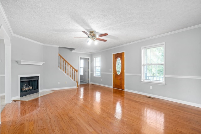 interior space with a ceiling fan, a fireplace with flush hearth, wood finished floors, visible vents, and stairway