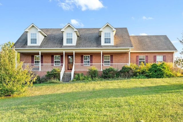 cape cod home featuring brick siding, roof with shingles, covered porch, and a front yard