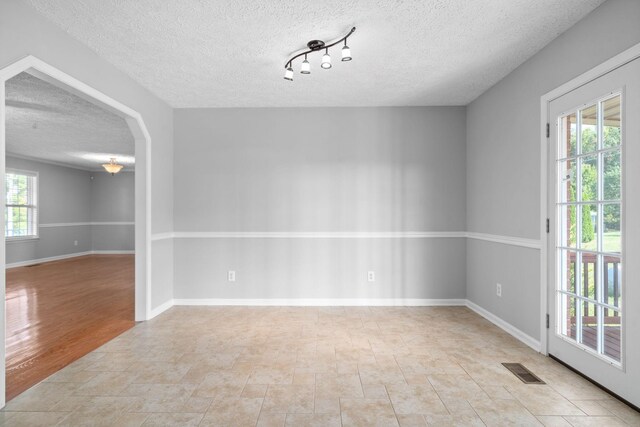 spare room featuring stone finish floor, baseboards, a textured ceiling, and visible vents