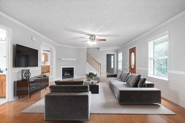living room with light wood-style floors, a fireplace, a ceiling fan, and a textured ceiling