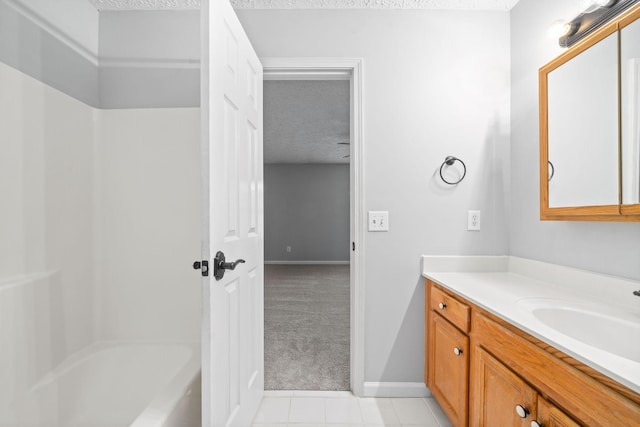 full bathroom with a textured ceiling, baseboards, tile patterned flooring, and vanity