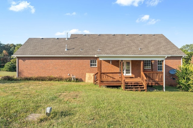 back of house featuring a lawn, roof with shingles, a wooden deck, and brick siding