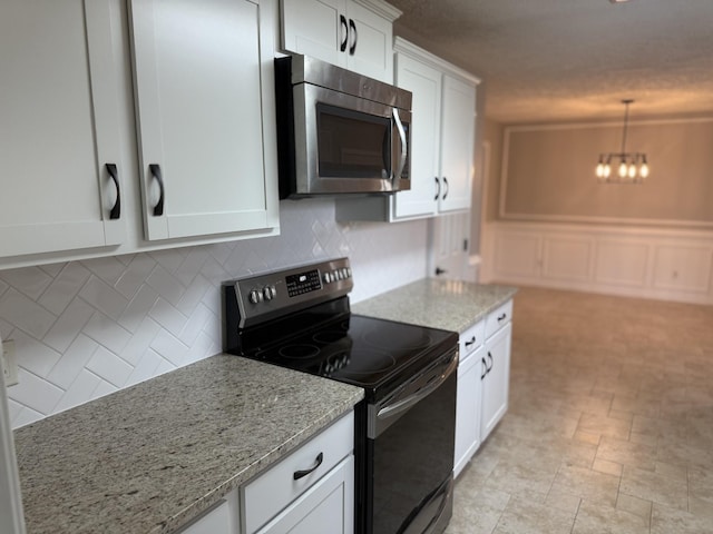 kitchen with electric range oven, a chandelier, white cabinetry, stainless steel microwave, and decorative backsplash