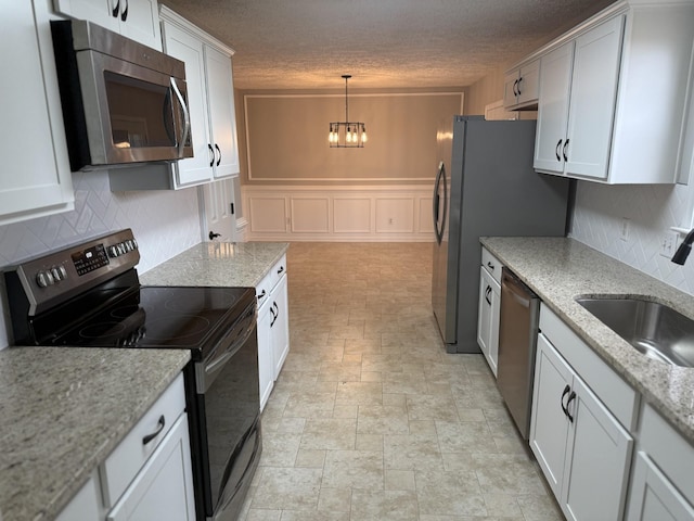 kitchen featuring stainless steel appliances, a notable chandelier, decorative backsplash, and a sink