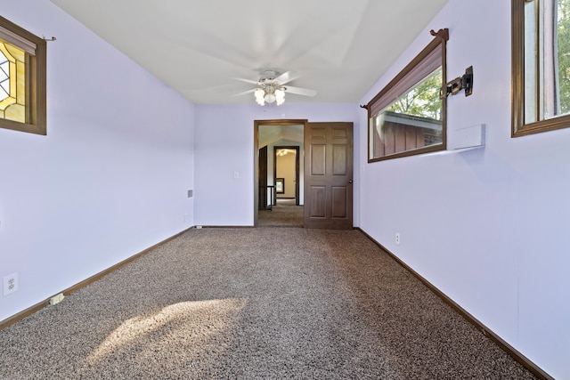 carpeted spare room featuring plenty of natural light and ceiling fan