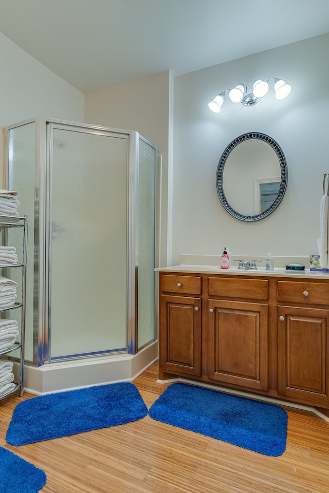 bathroom with wood-type flooring, a shower with door, and vanity