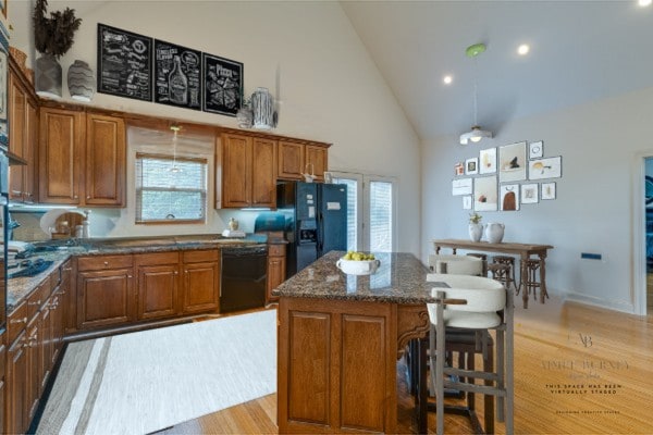 kitchen with high vaulted ceiling, black appliances, a center island, and plenty of natural light