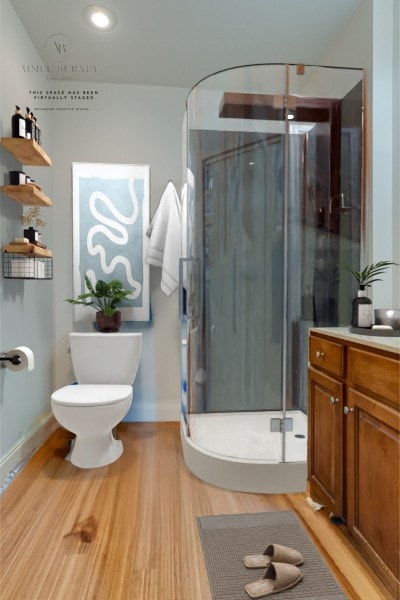 bathroom featuring vanity, toilet, wood-type flooring, and a shower with shower door