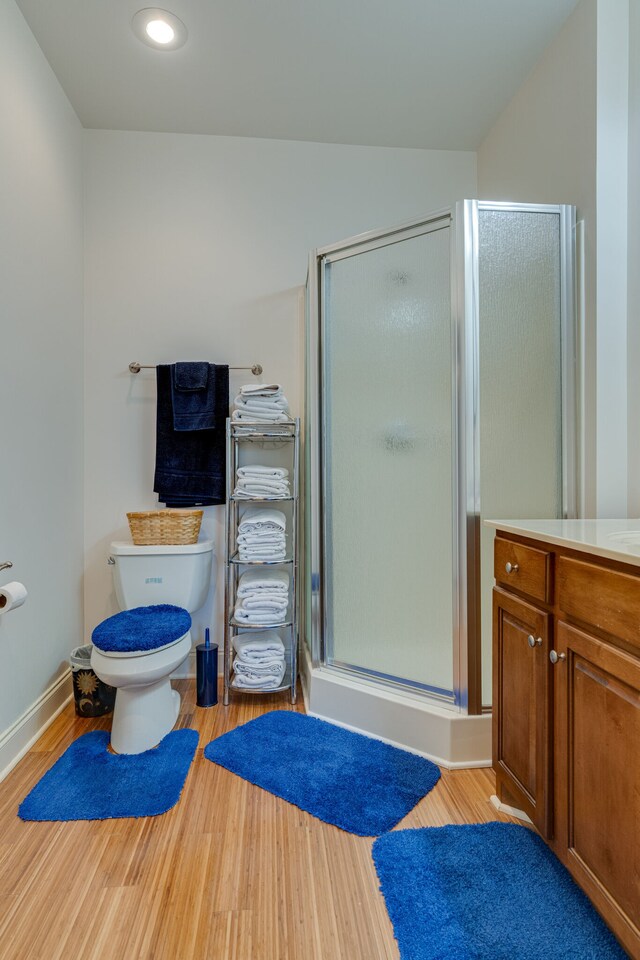 bathroom featuring vanity, toilet, hardwood / wood-style floors, and an enclosed shower