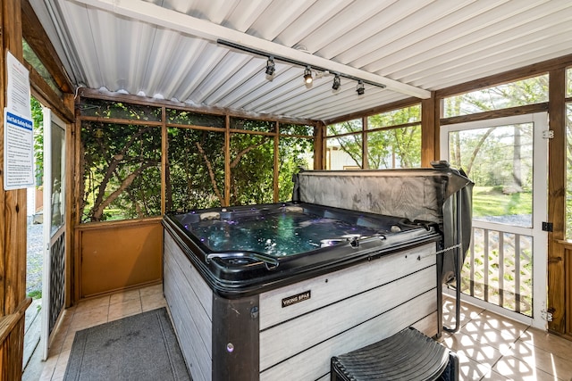 sunroom with a hot tub and rail lighting