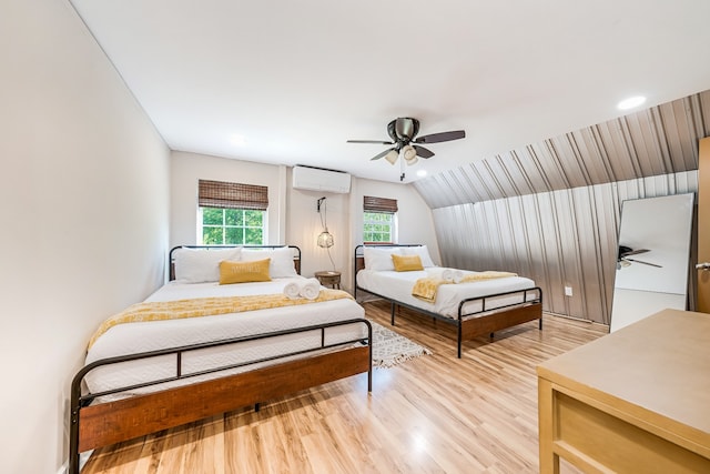 bedroom featuring lofted ceiling, ceiling fan, an AC wall unit, and light wood-type flooring