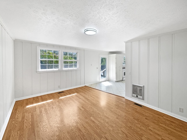 unfurnished living room with a textured ceiling, heating unit, and light hardwood / wood-style flooring