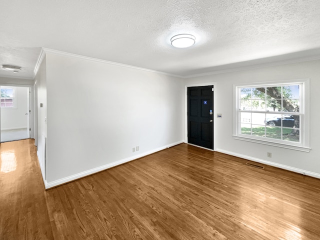 empty room featuring ornamental molding, a textured ceiling, and hardwood / wood-style flooring