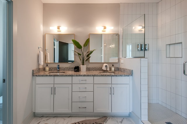 bathroom featuring toilet, a tile shower, and vanity