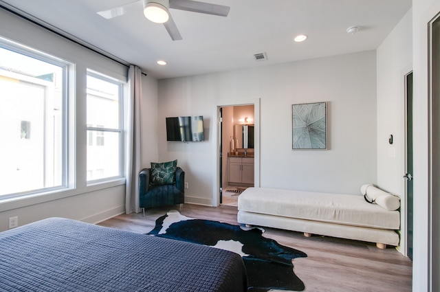 bedroom featuring ceiling fan, ensuite bath, and light hardwood / wood-style floors