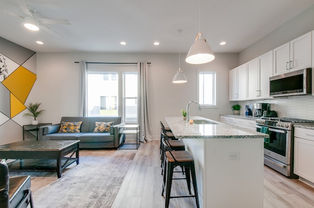 kitchen featuring white cabinets, stainless steel appliances, sink, and a center island with sink