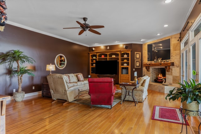 living room featuring hardwood / wood-style floors, ceiling fan, crown molding, and a brick fireplace