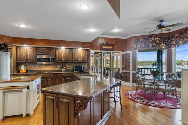 kitchen with a kitchen island with sink, crown molding, sink, ceiling fan, and light hardwood / wood-style floors